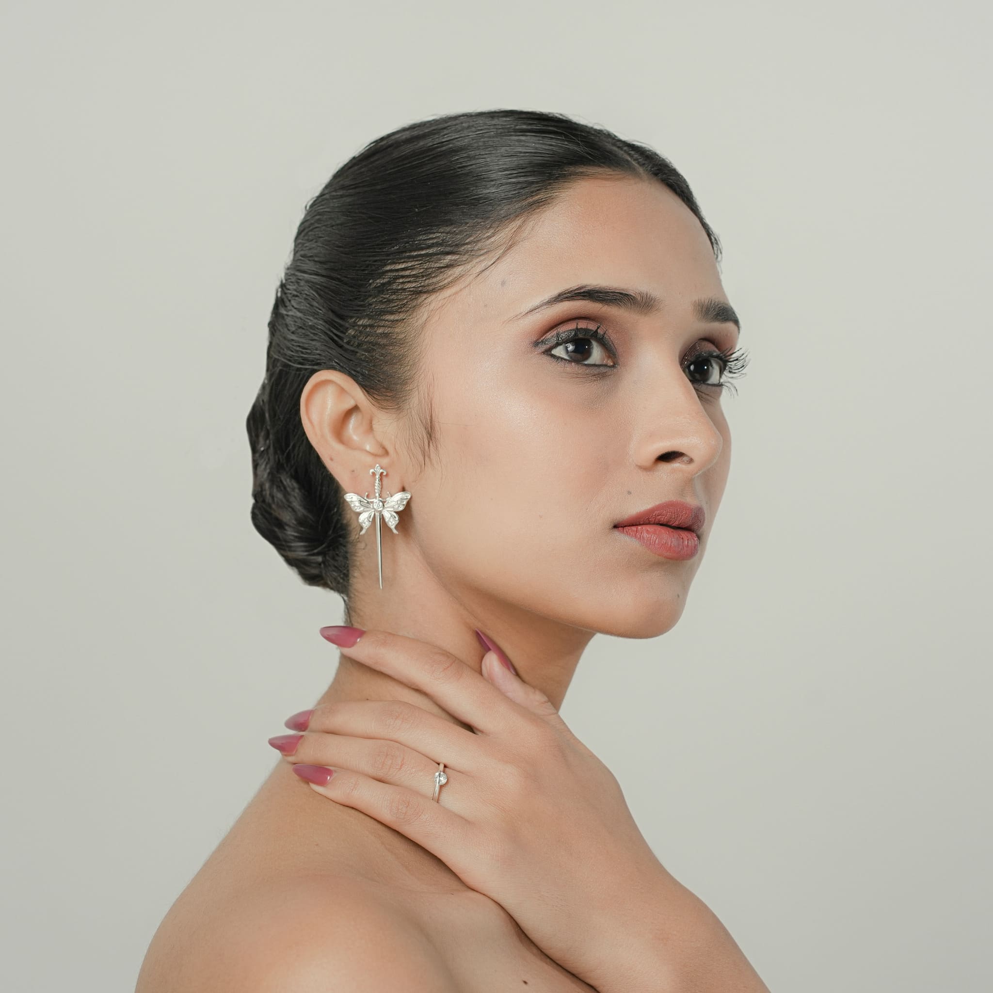 Model wearing silver sword stud earrings with CZ stones