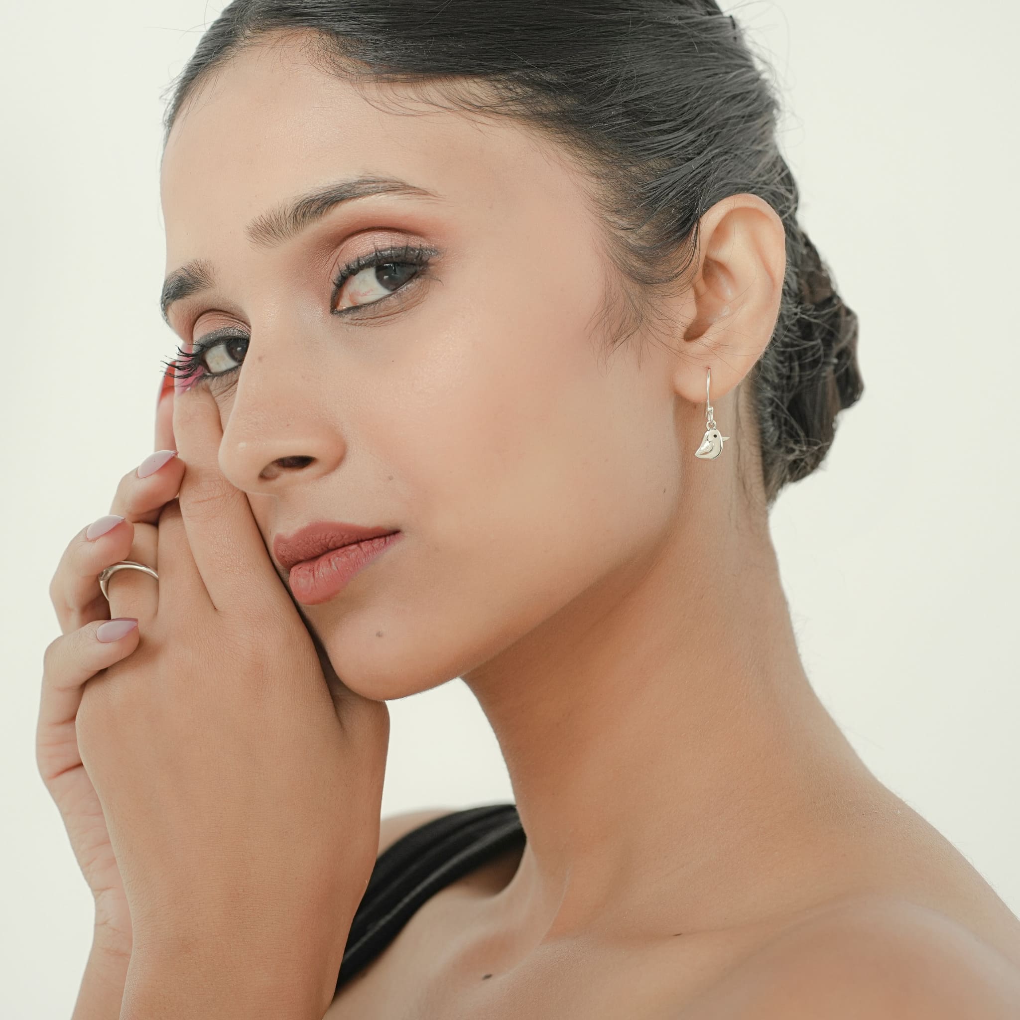 Model wearing silver bird pendant set with black enamel eyes