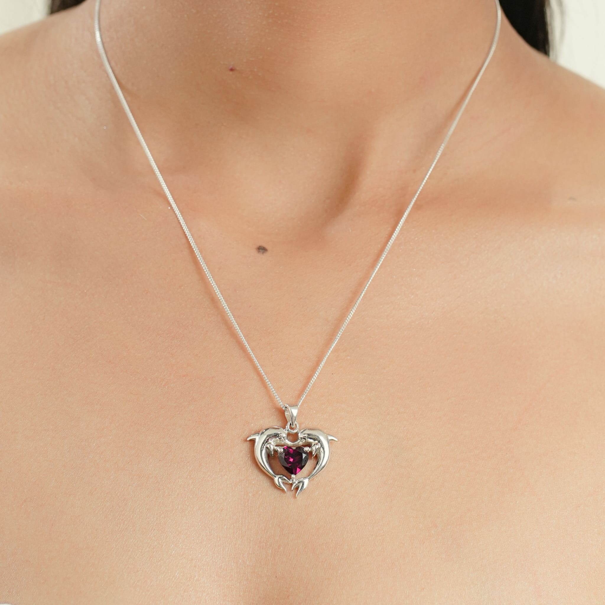 Model wearing silver dolphin heart pendant