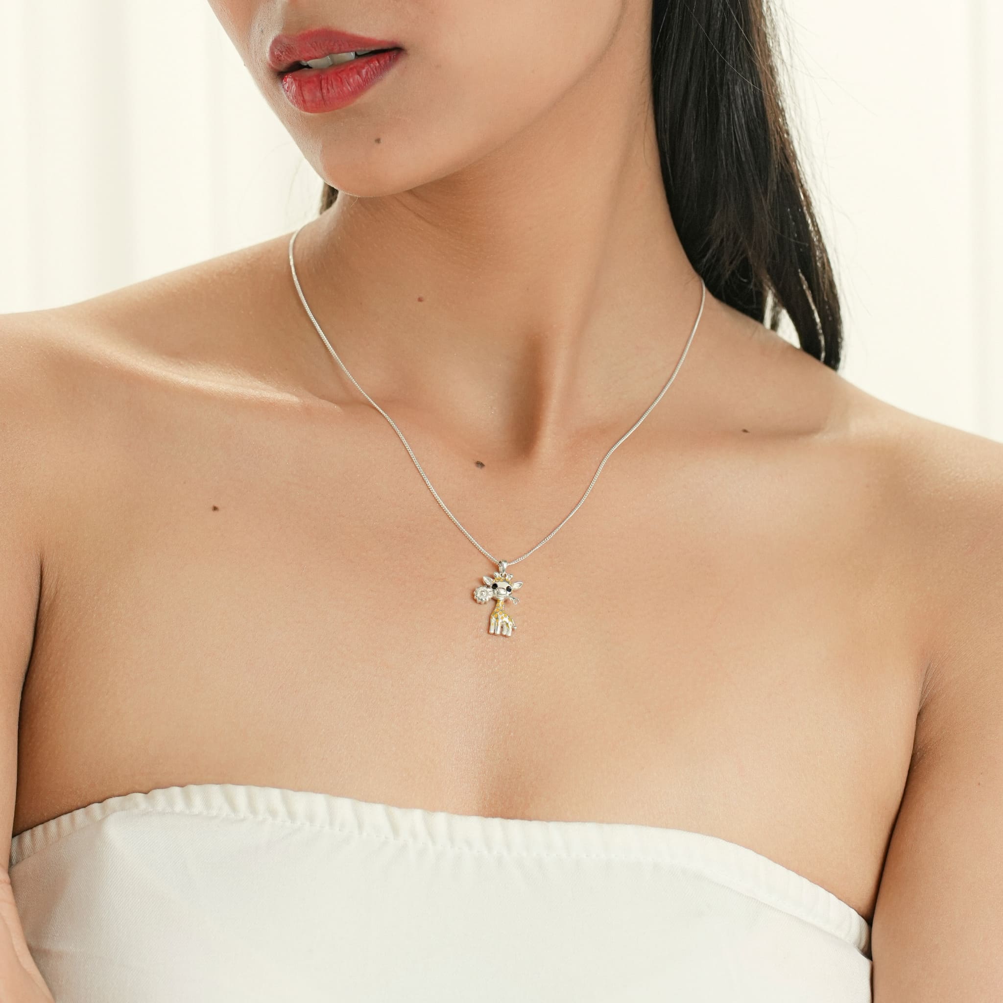 Model wearing silver and enamel giraffe pendant with black eyes