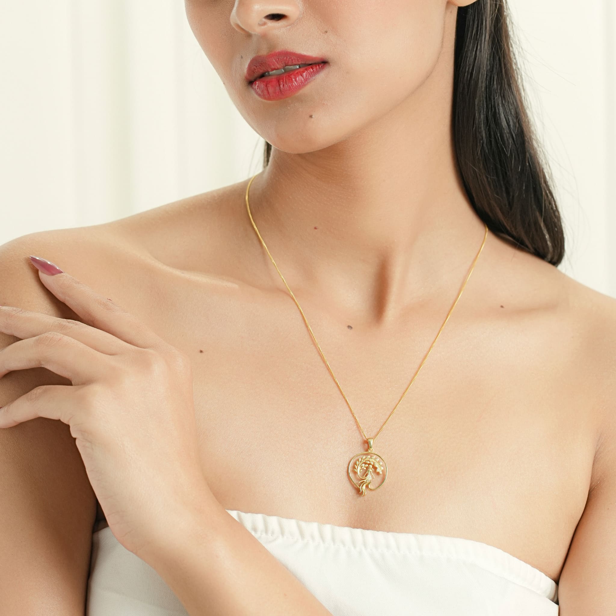 Model wearing gold-plated silver pendant featuring a girl sitting on a branch