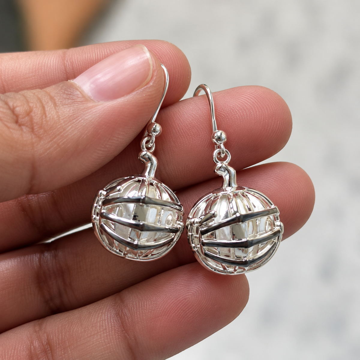 925 sterling silver pumpkin earrings with skeleton hand in black enamel detail. Unique gothic dangle earrings for Halloween, spooky styling and statement looks.
